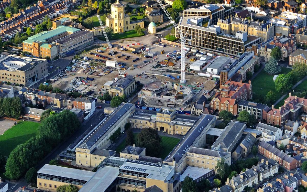 Aerial view of a construction site in Oxford with two tower cranes and a circular building under construction