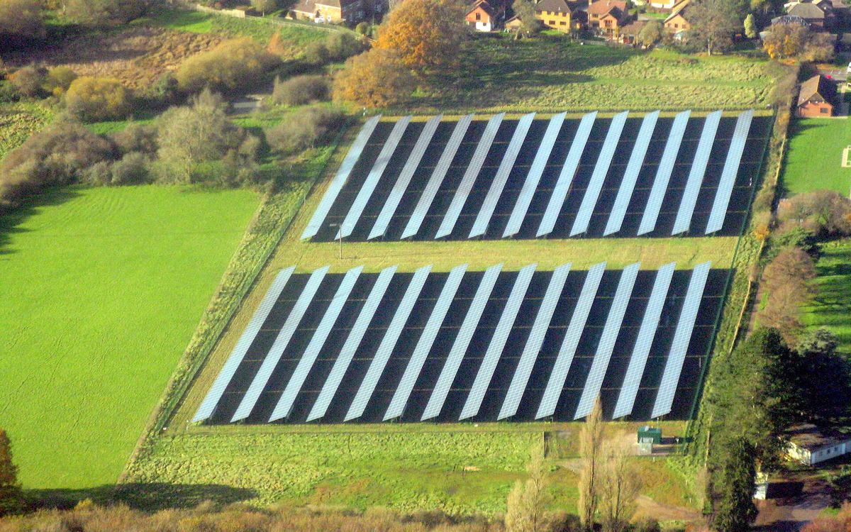 Aerial view of a solar farm at Otterbourne, Hampshire, with rows of panels beside green fields